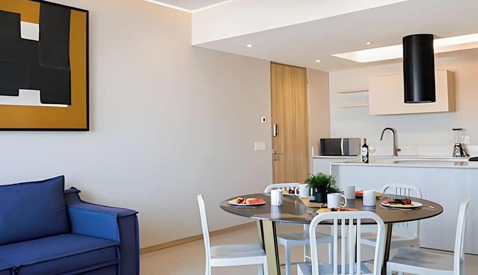 Bright living & dining area w/ blue sofa and table set for shared meals