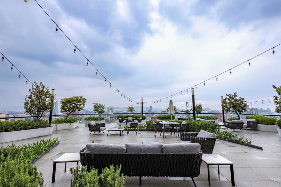 Shared rooftop patio w/ outdoor sofas & greenery, ideal for relaxing under the open sky