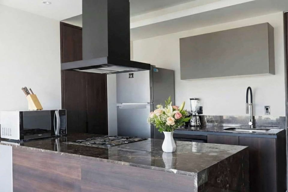 Sleek modern kitchen w/ island, cooktop hood & polished counters ready for home-cooked meals