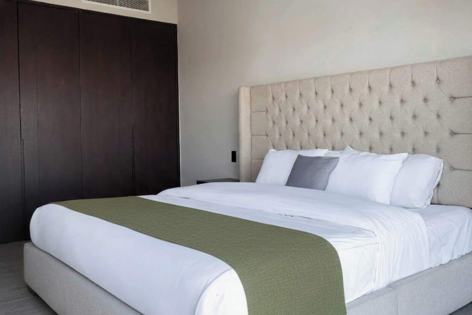 Inviting bedroom w/ plush bed, tufted headboard & soft green accent runner