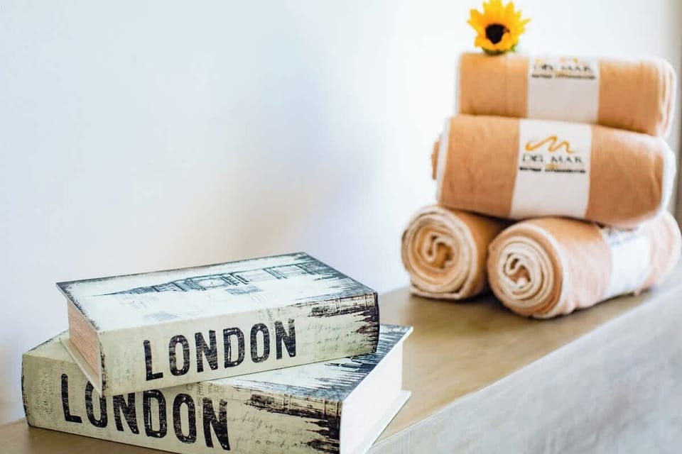 Styled decor detail w/ stacked books, rolled towels, and a fresh flower accent