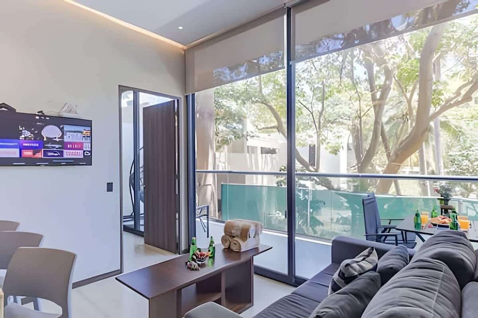 Cozy living area w/ sofa seating, TV & large windows opening to the balcony