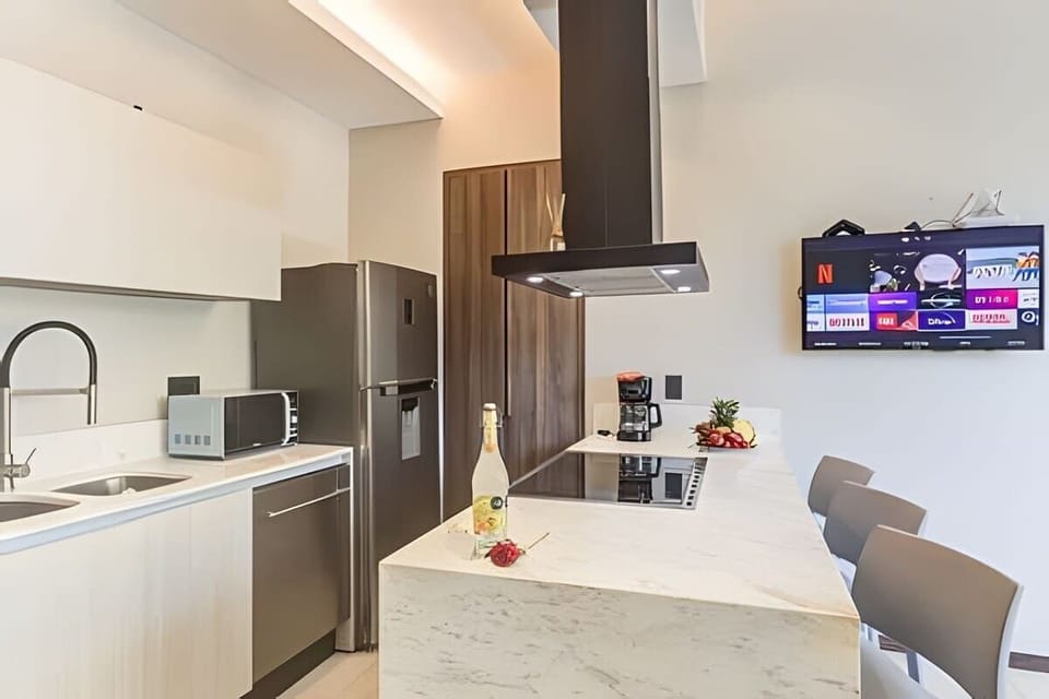 Sleek kitchen w/ island seating, modern cabinetry & TV for relaxed cooking or casual meals