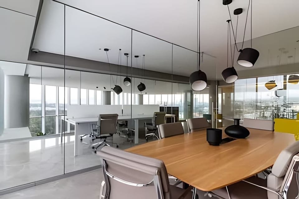 Shared glass-walled meeting room w/ long wood table, modern chairs & natural light throughout

