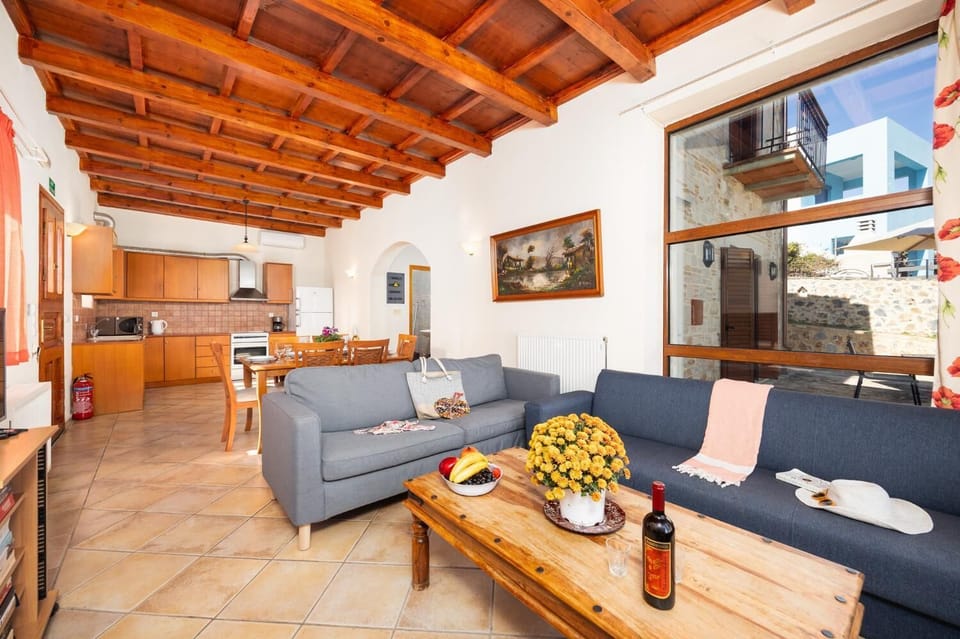 Open-plan living room with sofas, dining area, kitchen, ornamental fireplace, A/C, WiFi internet, and satellite TV
