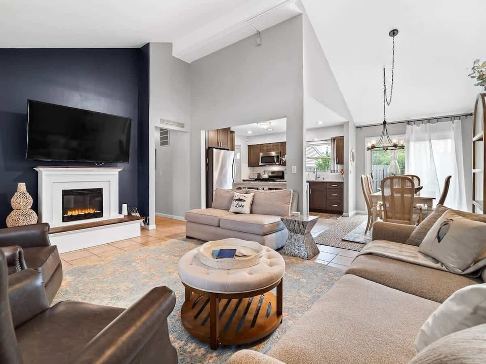 Inviting living room with fireplace and mounted TV . Plush seating and natural light from large windows create a perfect spot to relax. The open layout flows effortlessly from entryway to lounge ️.