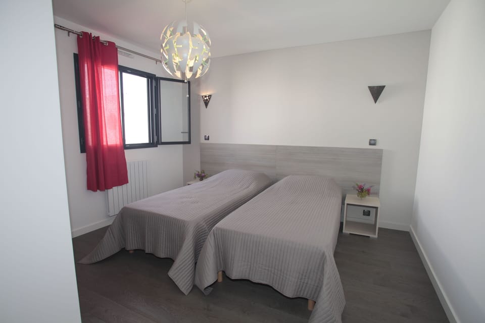 Twin bedroom bathed in natural light, offering flexibility for families or groups.