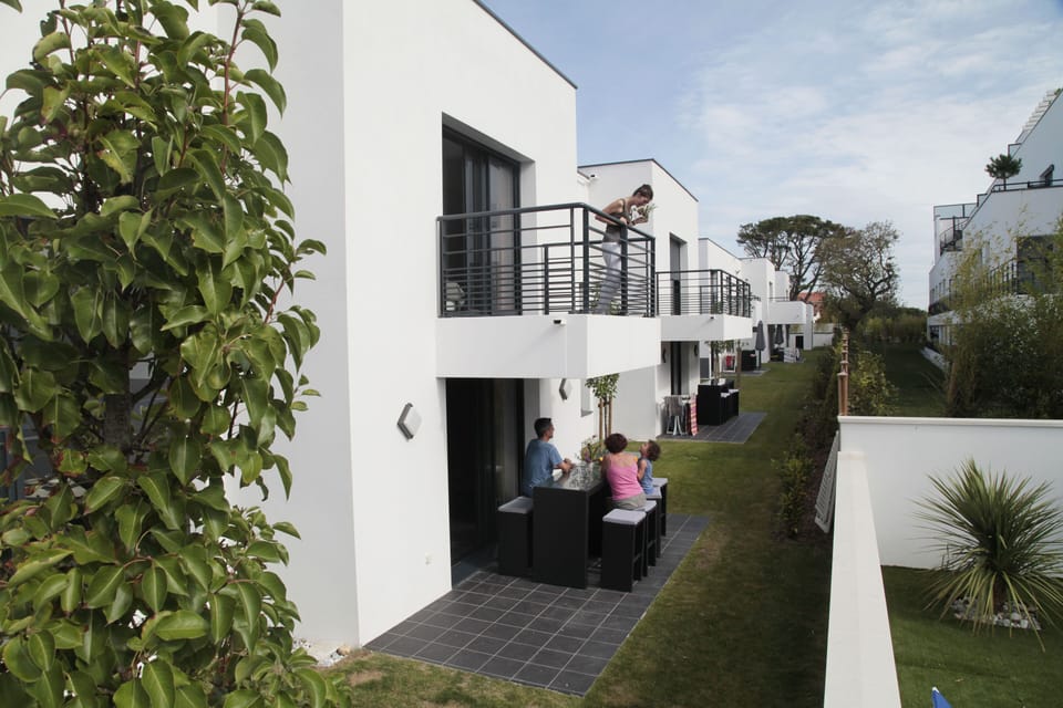 Chic villa exterior with minimalist design, opening onto a private, furnished terrace—ideal for lounging or alfresco dining.
