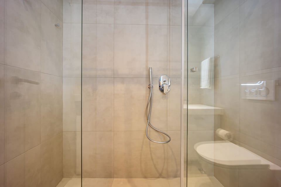 Minimalist shower space with sleek finishes, offering refreshing simplicity and modern relaxation in Athens.

