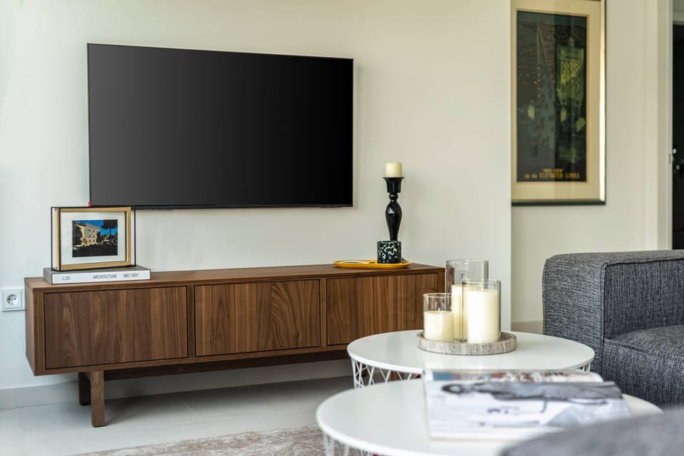 Modern lounge with entertainment setup, admired for thoughtful decor and inviting atmosphere throughout Athens apartment.