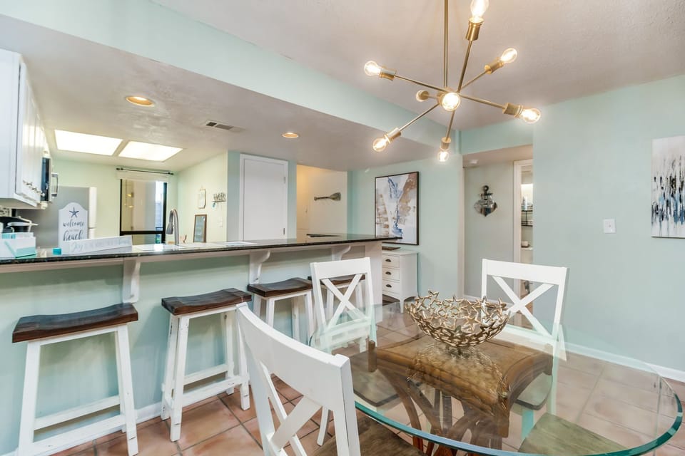 Open-concept dining with comfortable seating for 4 and stunning Old River views at Wind Drift Orange Beach bayfront condo Fully equipped kitchen with stainless appliances and tile countertops with breakfast bar for 4 at Wind Drift Orange Beach waterfront v