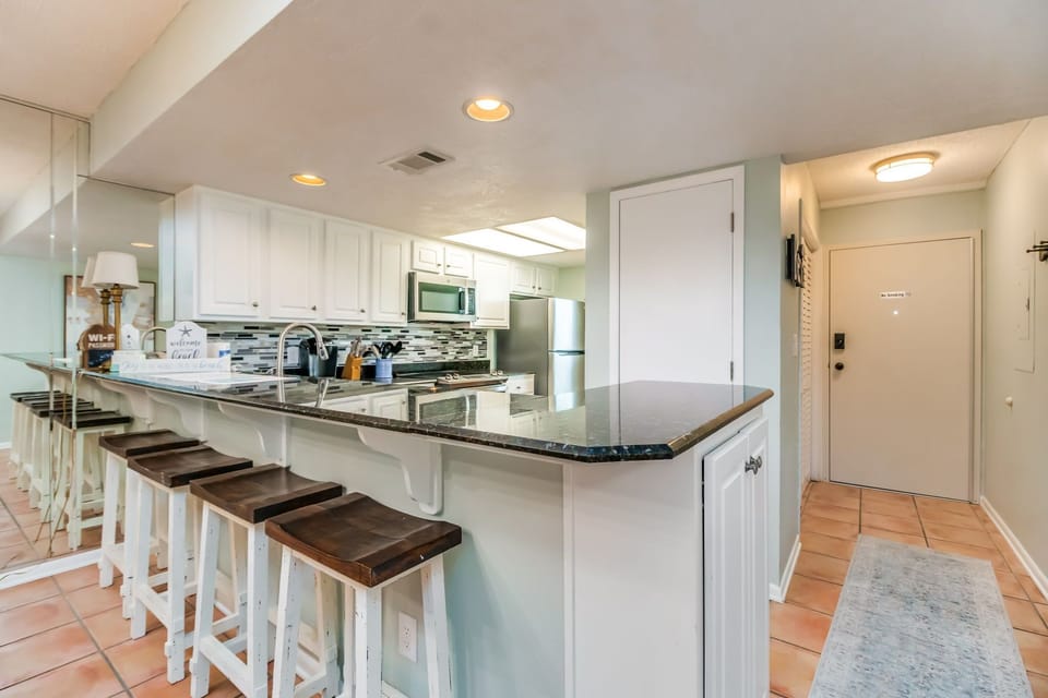 Fully equipped kitchen with stainless appliances and tile countertops with breakfast bar for 4 at Wind Drift Orange Beach waterfront vacation rental