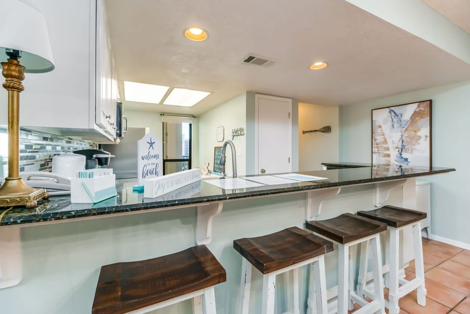Fully equipped kitchen with stainless appliances and tile countertops with breakfast bar for 4 at Wind Drift Orange Beach waterfront vacation rental