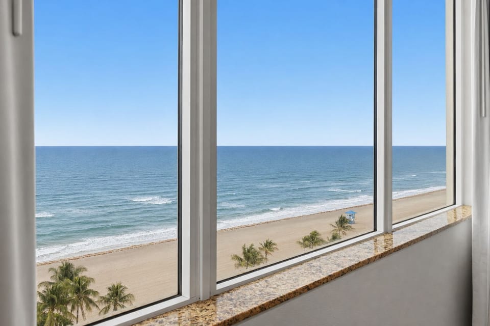 Ocean view framed by windows with palm trees along the beach.