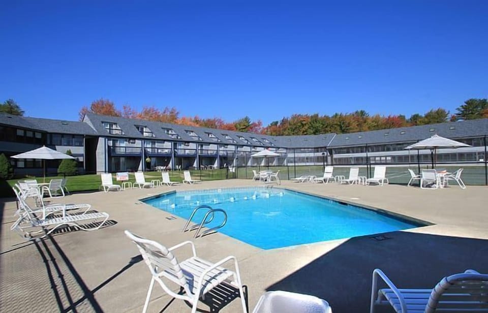 Lounge by the refreshing outdoor pool surrounded by stylish deck seating and modern resort architecture.