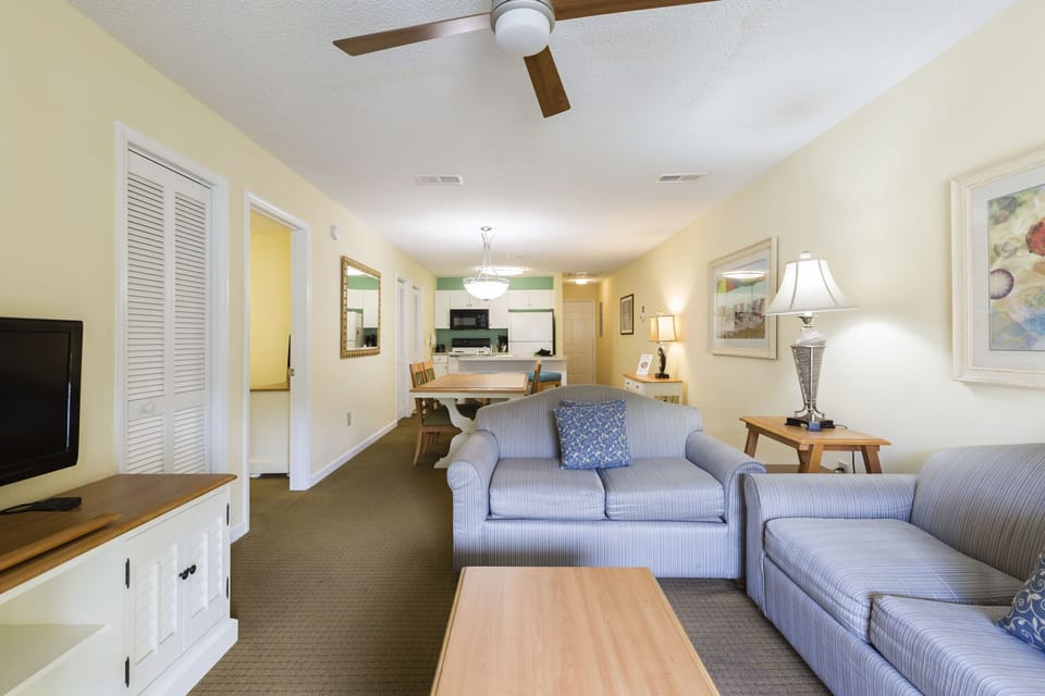 Enjoy the open-concept living area with comfortable seating, a flat-screen TV, and easy access to the dining area and full kitchen.