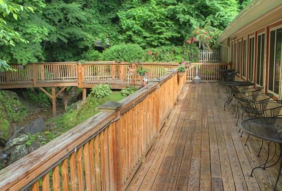 A scenic wooden deck surrounded by lush greenery offers a peaceful outdoor space for relaxation, perfect for enjoying the beautiful mountain setting.