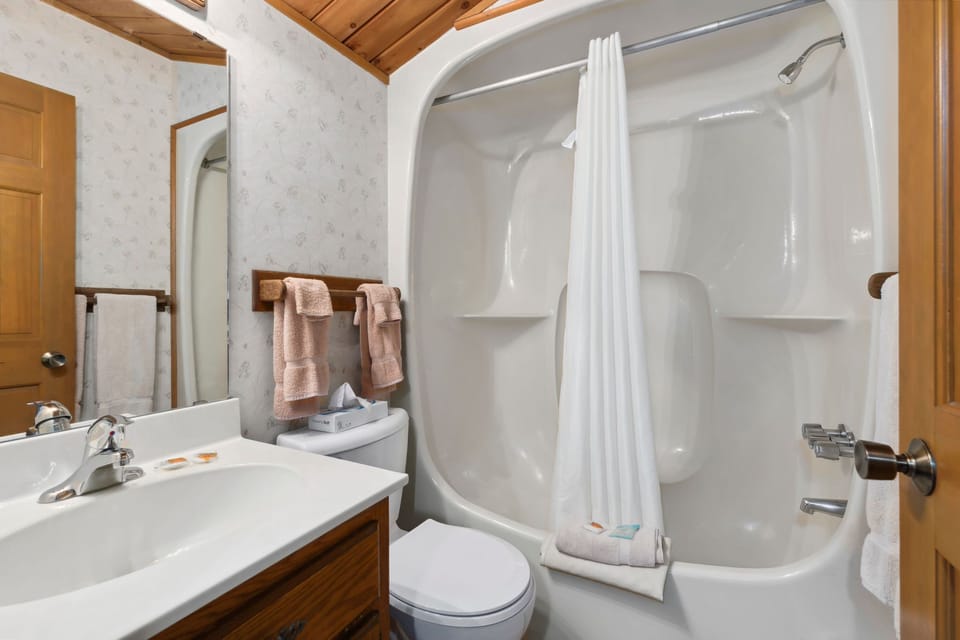 Full bathroom with a shower-tub combo, vanity, and rustic wood accents.