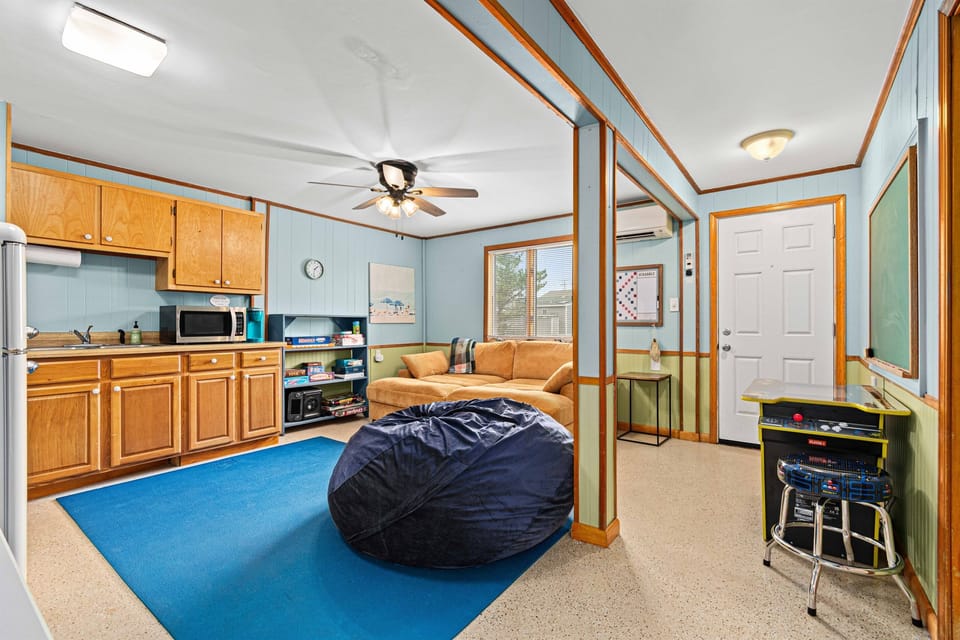 Detached from the main level spaces, this playroom features a kitchenette, oversized comfy couch, Pac-Man arcade table, and board games.  Ideal hangout spot for kids of all ages.  