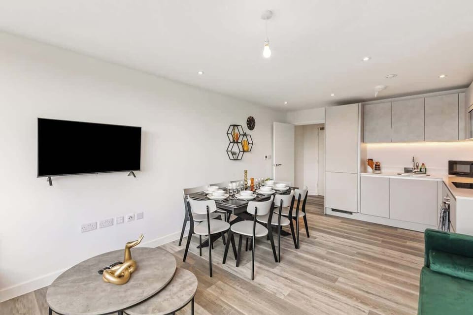 - Dining table set for group meals beside modern kitchen  
- Flat-screen TV adds entertainment to bright open-plan stay  
- Spacious Airbnb interior for families or business guests  