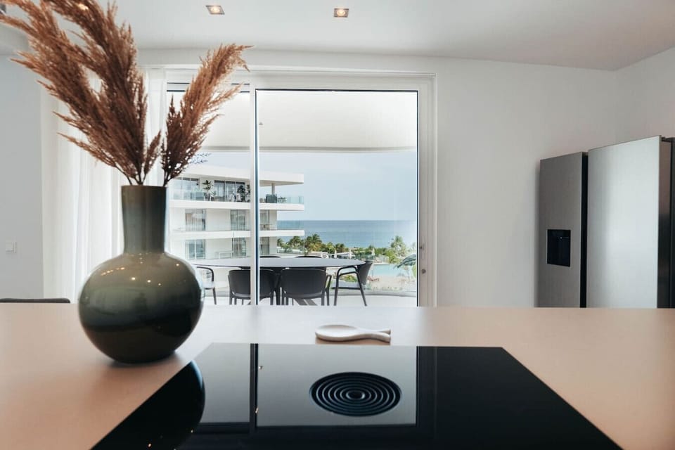 Brew a fresh cup and start your morning with a view! This modern kitchen features a sleek stovetop and a large island that overlooks the turquoise ocean, making every meal feel like a special occasion.