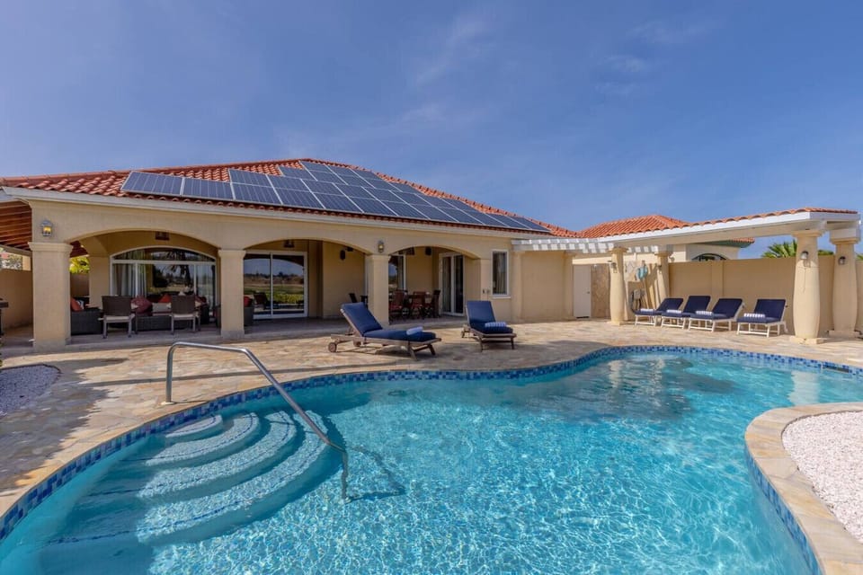 Beautiful home featuring a private pool with comfortable lounge chairs, perfect for relaxation. The spacious outdoor area is complemented by a pergola, and the house is equipped with solar panels, offering both luxury and sustainability.