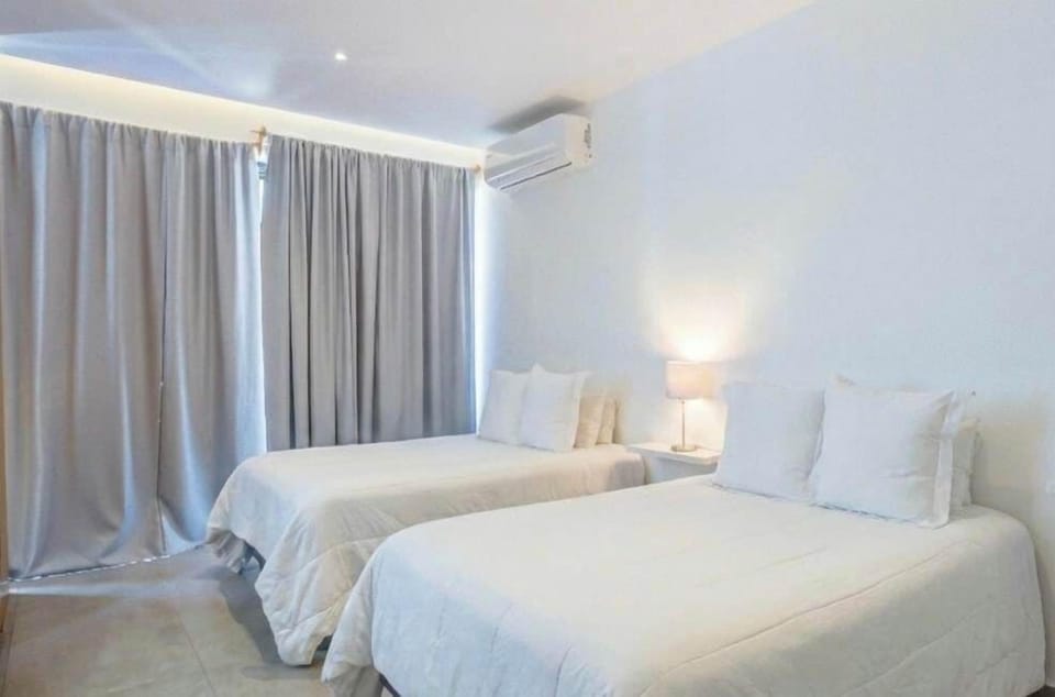 Calm bedroom w/ two beds, soft lighting & floor-to-ceiling curtains