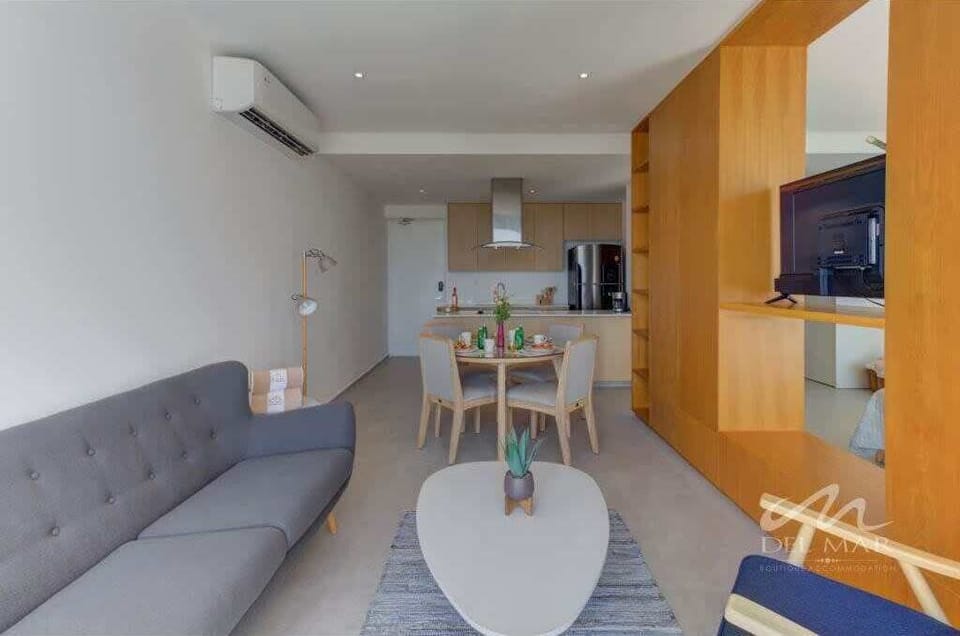 Open living area w/ sofa, TV & dining table extending into the kitchen
