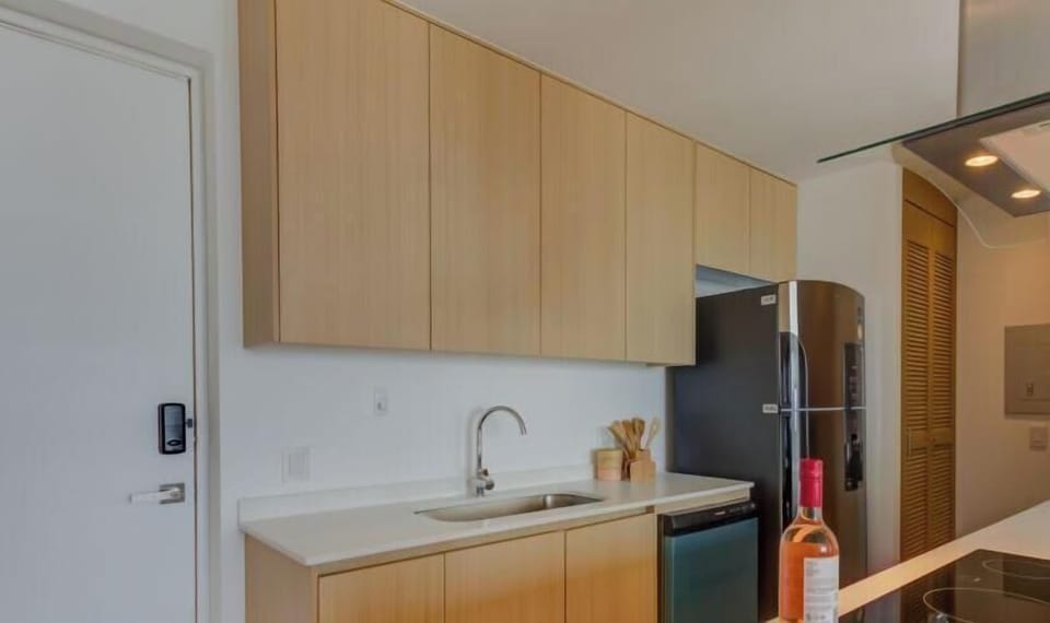 Modern kitchen w/ wood cabinetry, sleek counters & open layout to the living area