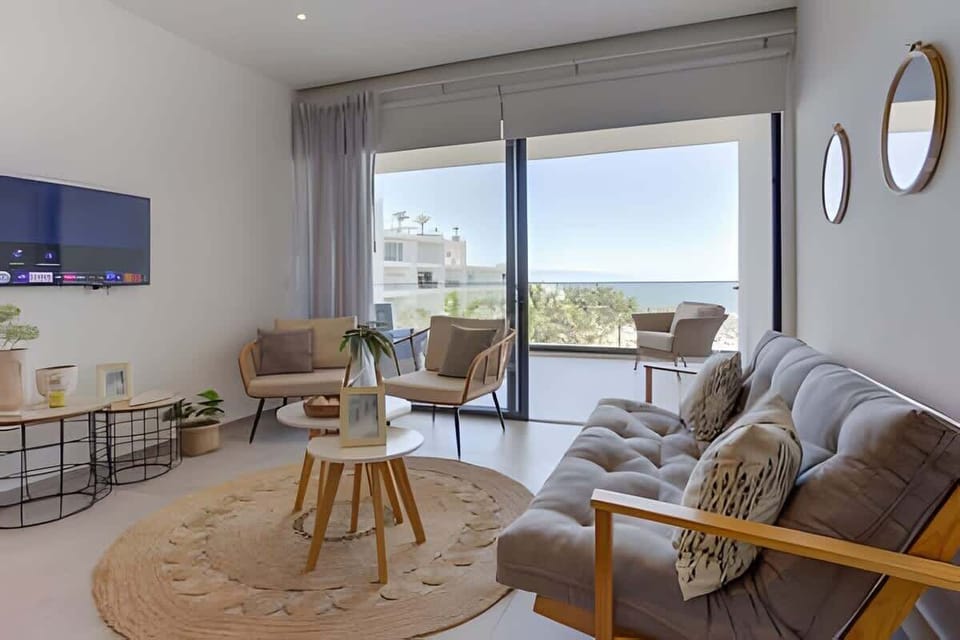 Sunlit living room w/ sofa seating, lounge chairs & large windows framing the view