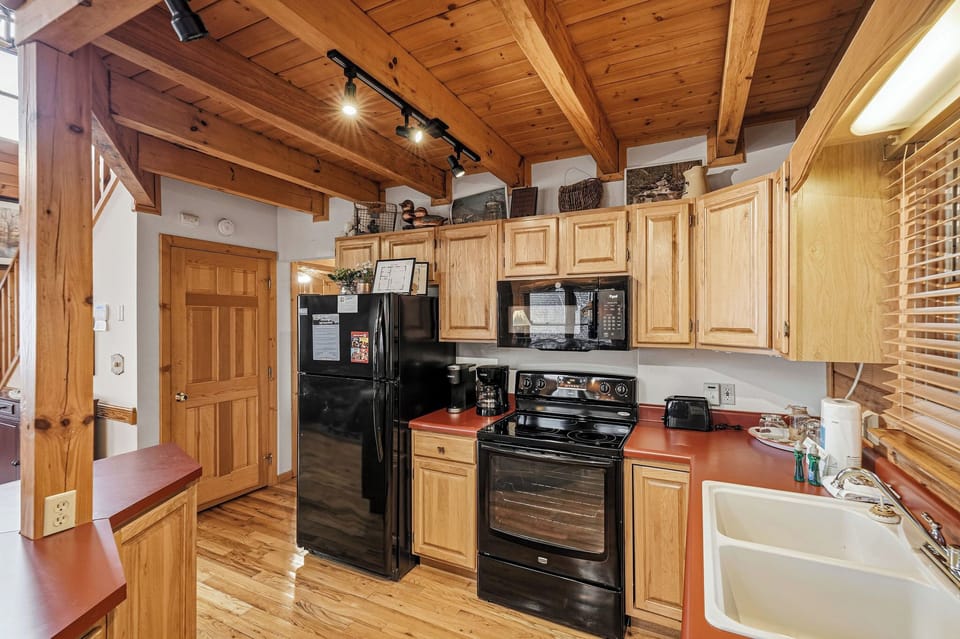 Your fully equipped kitchen awaits with warm wood details, modern appliances, and rustic charm under exposed beams.