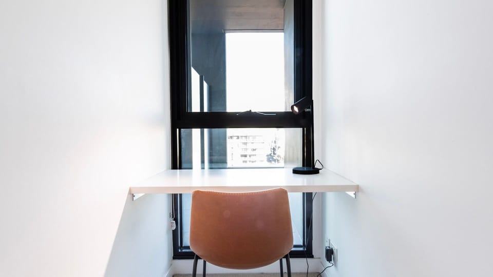 A minimalist, space-saving desk sits perfectly tucked under a bright window to create an inspiring study nook.
