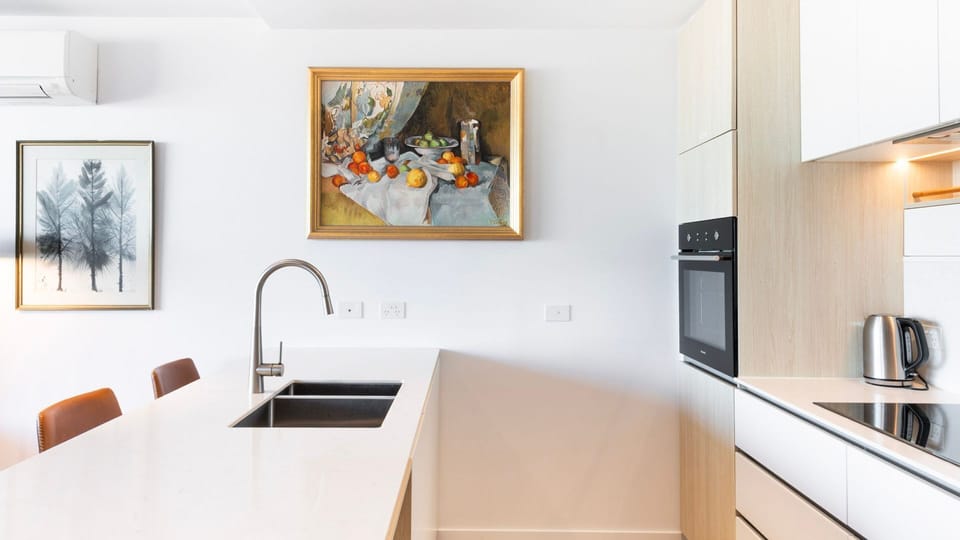 Classic framed artwork adds an elegant, personal touch to the crisp white walls of this contemporary kitchen.