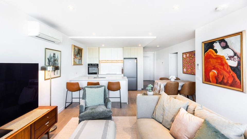 This comprehensive view highlights the apartment's seamless, fluid transition from the kitchen and dining room to the main lounge.