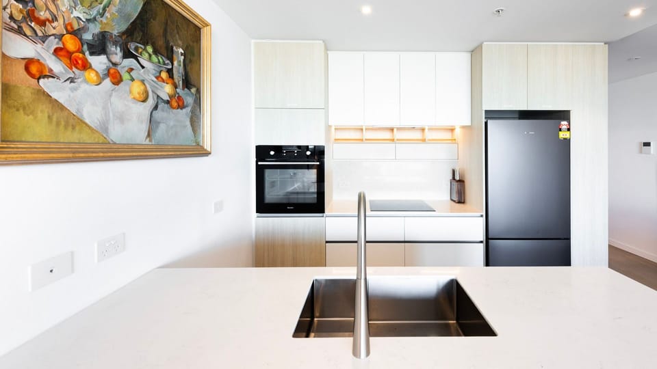 A pristine white waterfall island anchors this sleek, ultra-modern kitchen setup.