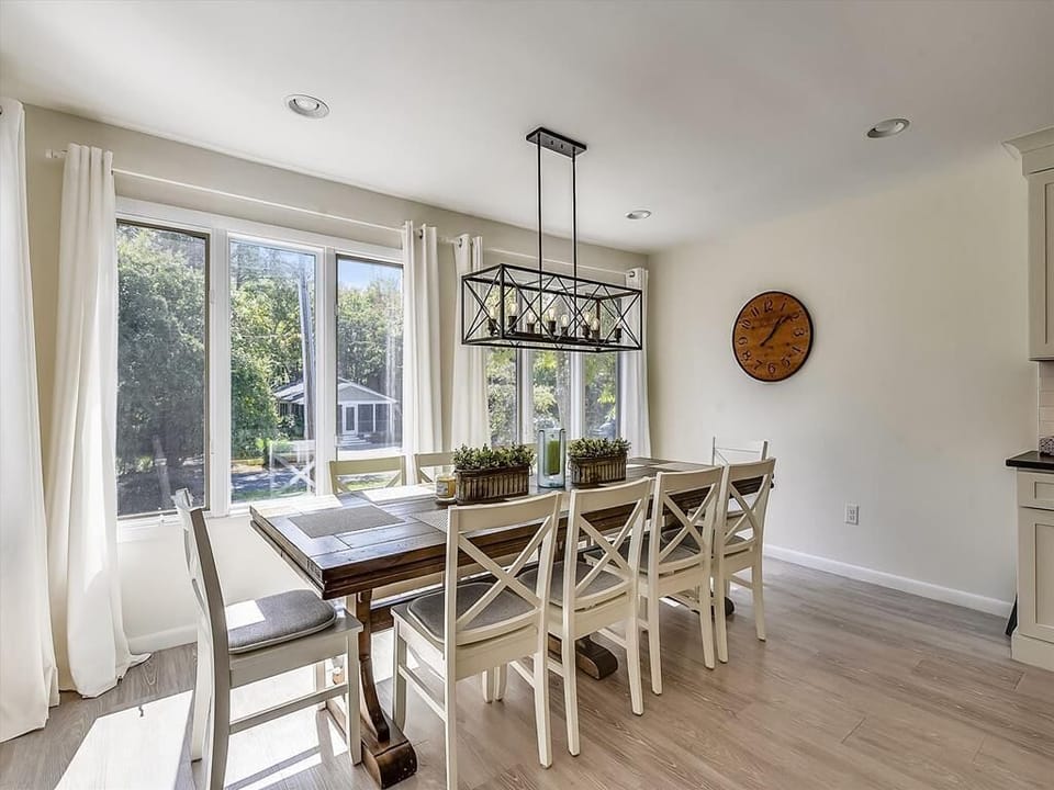 The elegant dining area is bathed in natural light through large windows, providing a welcoming space for family gatherings while enjoying the view of the lush surroundings.