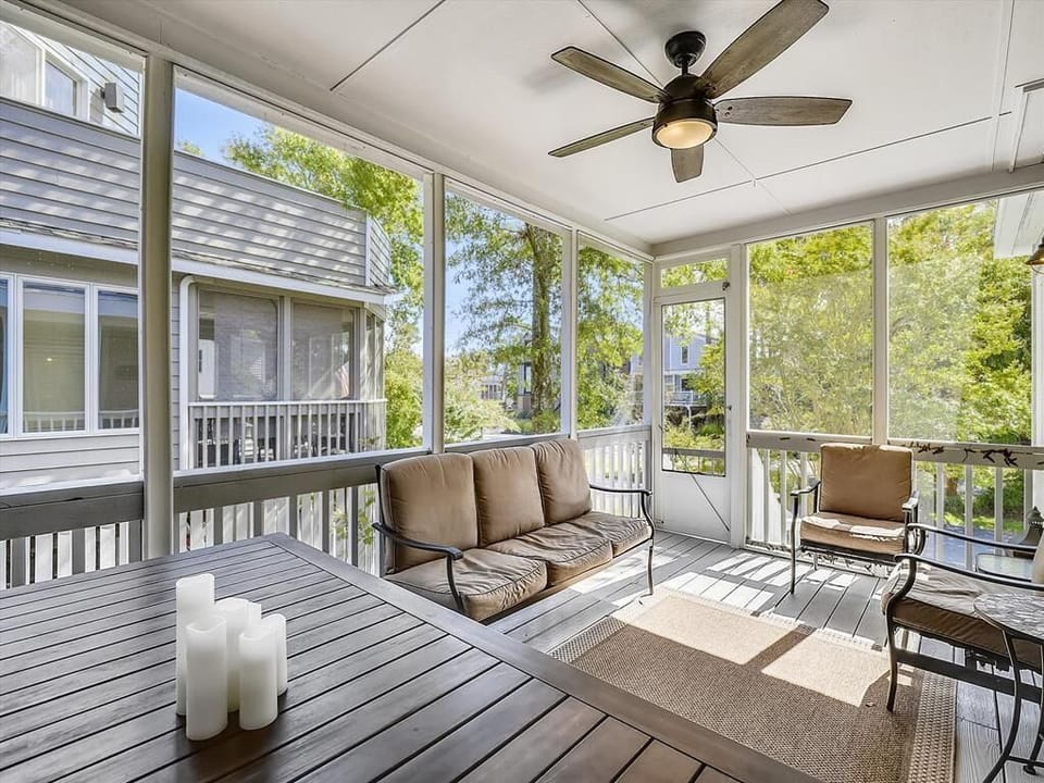 Bathed in natural light, the screened porch offers a cozy retreat with plush seating, ideal for savoring the coastal breeze while staying sheltered from insects.