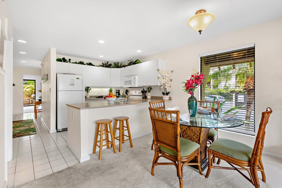 Comfortable dining area with a table for four, next to a functional kitchen with a breakfast bar.