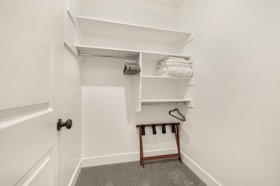 Walk-in closet in the Queen bedroom. Luggage rack, hangers, extra bedding.
