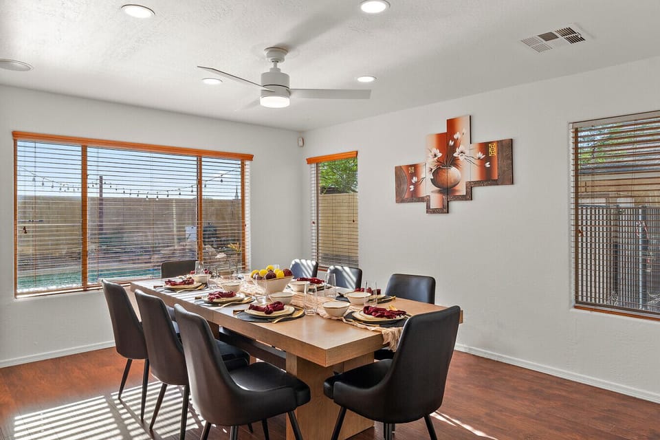 Bright dining room with stylish seating for eight and large windows offering beautiful views of the pool and backyard oasis.