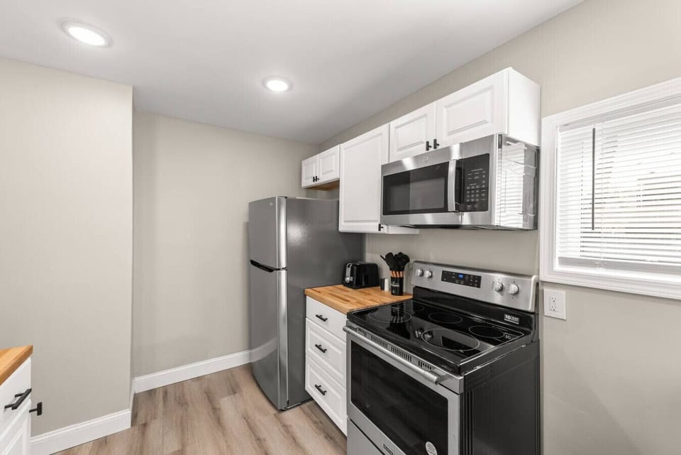 Prepare meals with ease in the bright kitchen featuring stainless steel appliances, butcher block countertops, ample cabinetry, and natural light.