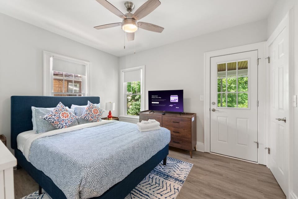 Spacious queen bedroom with a Smart TV, premium bedding, and plenty of natural light for a comfortable stay.