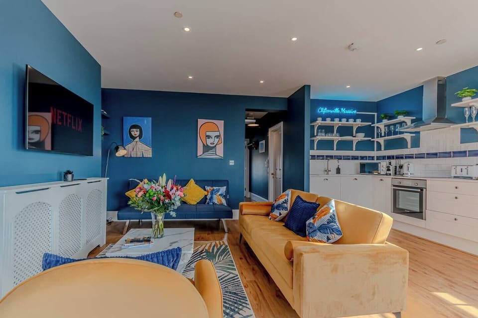 🛋 Living Room / Lounge
Soak up panoramic sea views in this vibrant, design-led living space. Featuring rich navy walls, statement artwork, elegant period features, and tall sash windows, the lounge invites you to relax in comfort. Sink into plush seating, stream your favourite shows on the Smart TV with Netflix, or simply enjoy the ever-changing coastal light show.
