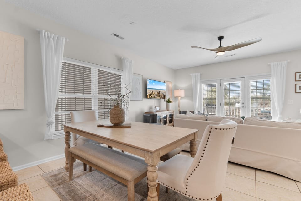 Gather around the dining table where natural light pours through large windows, or relax in the bright living room with a ceiling fan and TV—perfect for unwinding after exploring nearby attractions.