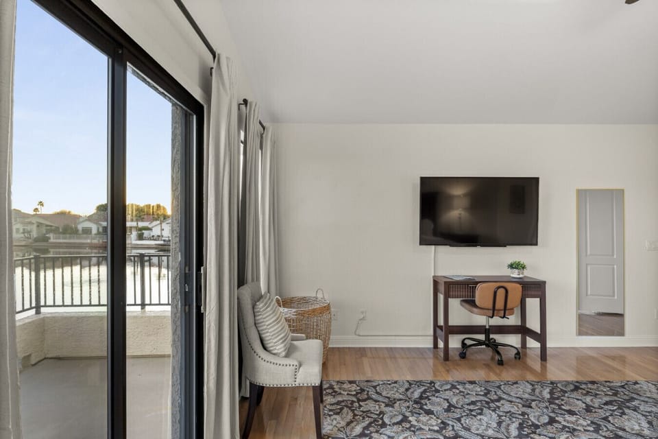 Stay productive in this master suite featuring a dedicated laptop-friendly workspace, large smart TV, and direct balcony access.