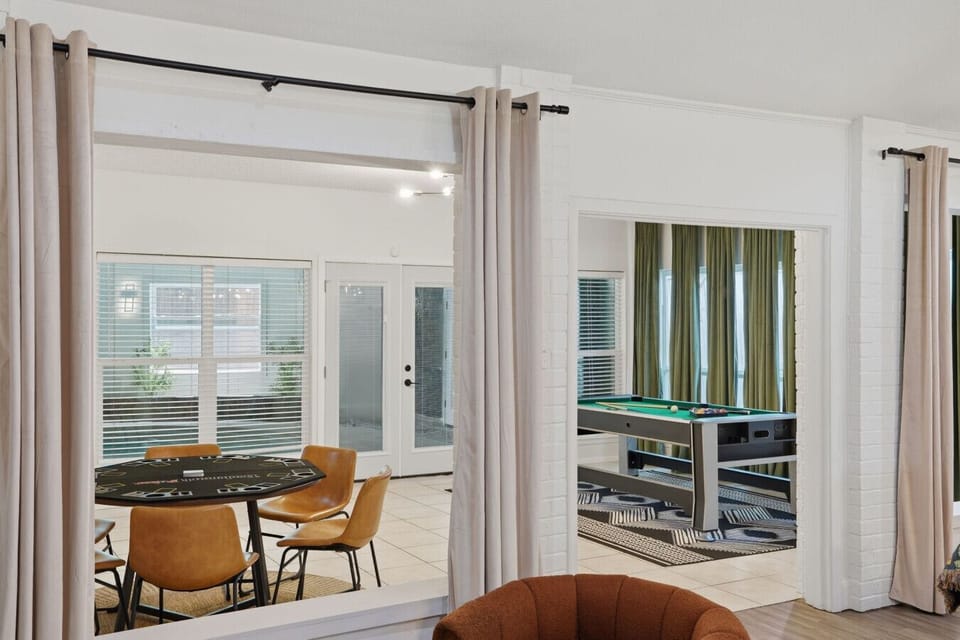 Peek into two incredible entertainment rooms from the entryway — a poker and card game table with leather chairs on the left, and a full billiards/pool table room with green velvet drapes on the right. Entertainment at every turn!