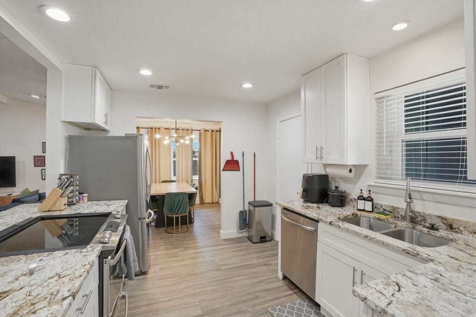 Chef-ready kitchen with a stainless steel gas range, ample granite prep space, white cabinetry, and fully stocked cookware — everything you need to prepare meals for the whole group during your Irving, TX vacation rental stay