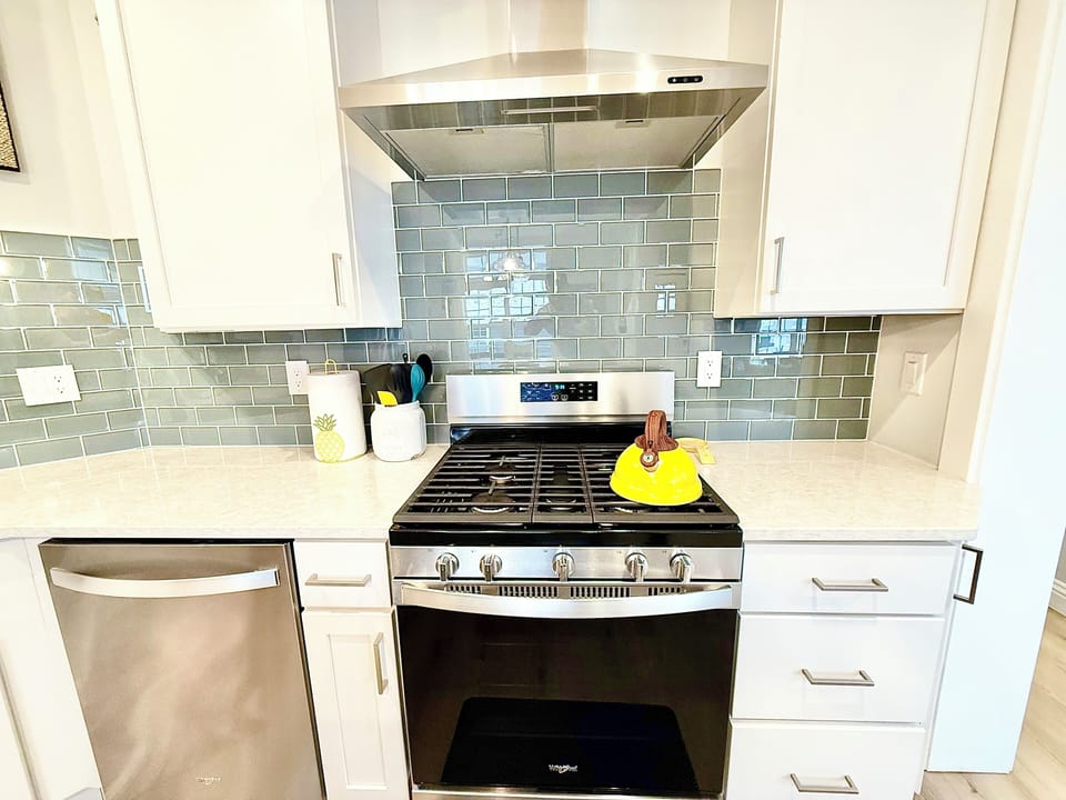 Cook with ease on this modern gas stove, set against a sleek glass tile backsplash, adding both style and function to your stay.