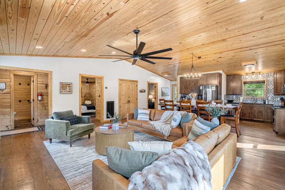 The living room on the Main Level is light and bright with large windows, a 65` Samsung Smart TV, modern linear electric fireplace, and a vintage-style record player—perfect for relaxing with a glass of wine, charcuterie, and a good Dolly record.