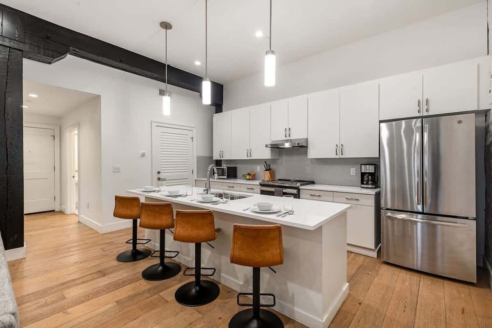 Fully equipped kitchen featuring stainless steel appliances, open counter space, and bar seating for 4 guests.